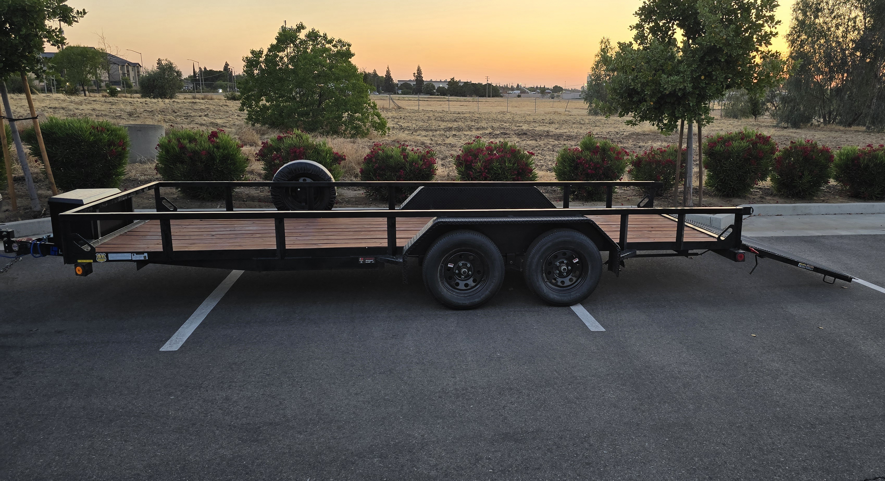 Side view of Express Trailer Rentals utility trailer showing dual axle construction and tie-down points
